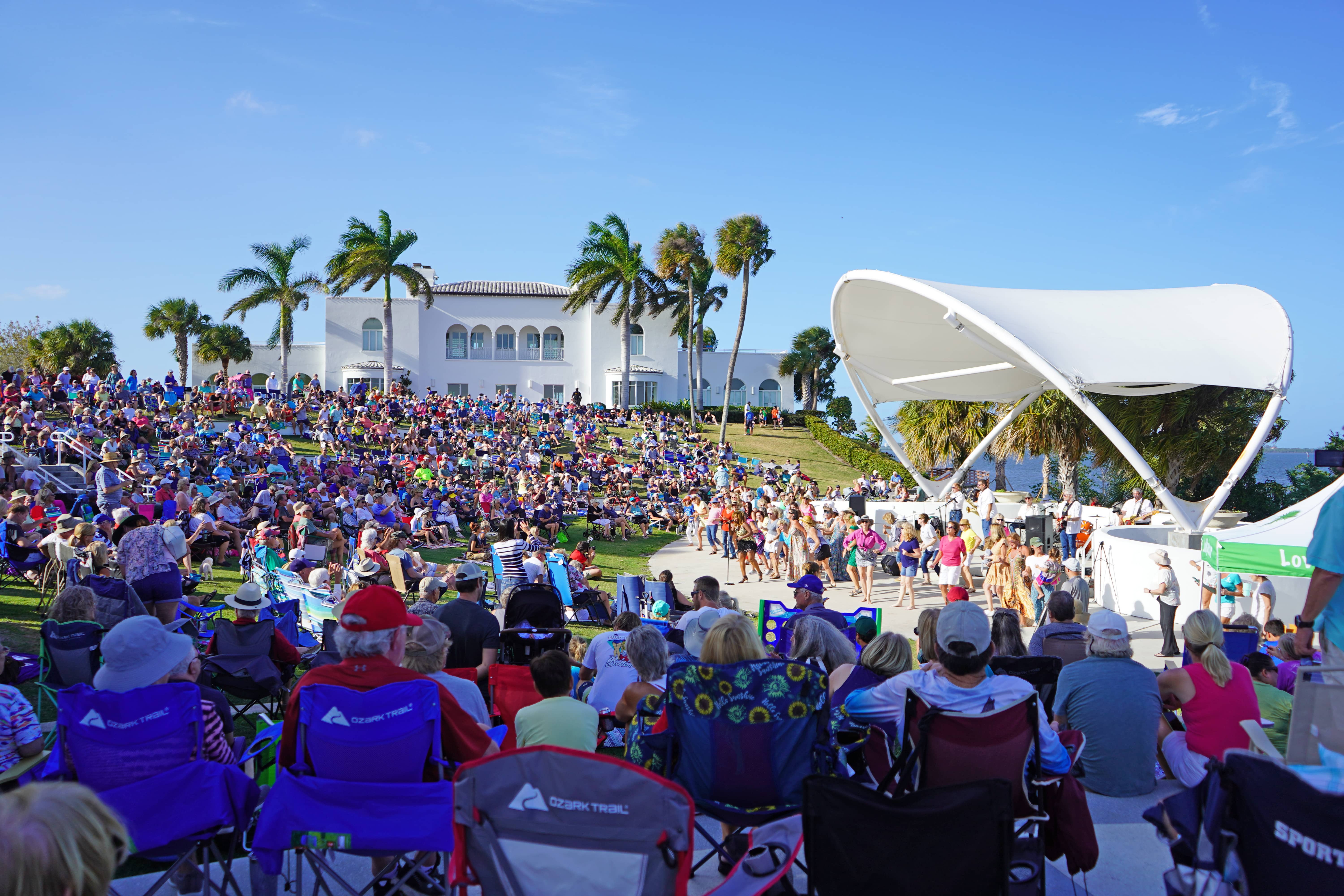 Image of a large crowd surrounding the Mansion at Tuckahoe in Jensen Beach, Florida, as they listen to a band playing at the Music at the Mansion event