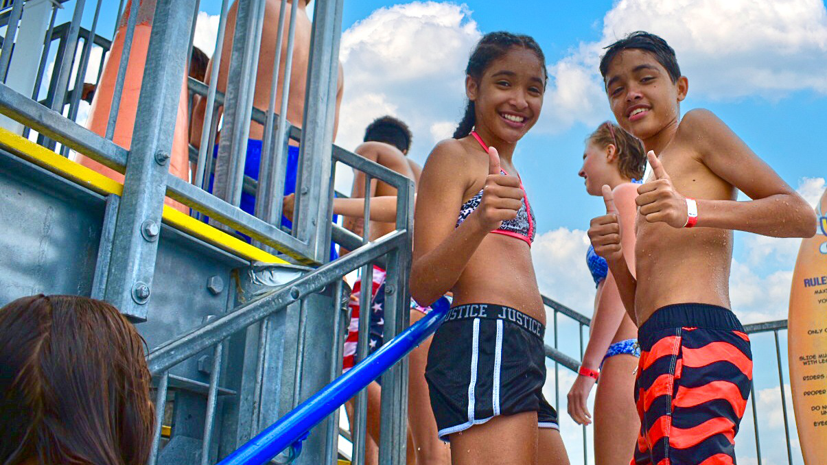 Image of a brother and sister smiling with a thumbs up while waiting to go on the tower waterslides at Sailfish Splash Waterpark in Stuart, FL. 