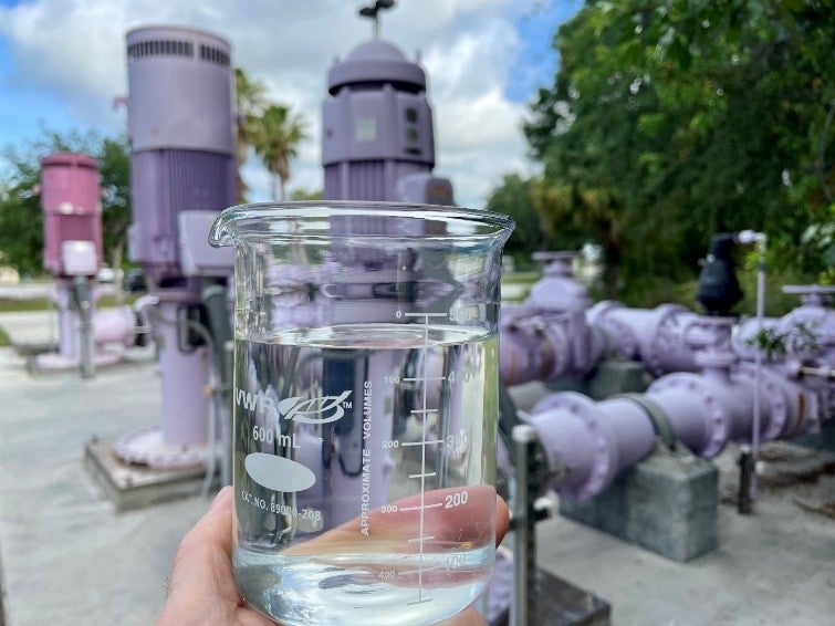 A hand holding reclaimed water in a glass