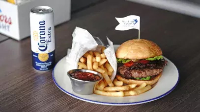 Image of a Sailfish Sands burger with a side of fries and a can Corona Extra