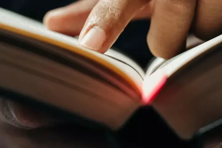 finger on the page of an open book