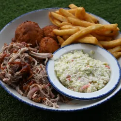 chopped BBQ plate featuring pulled pork, French fries, hush puppies and coleslaw.