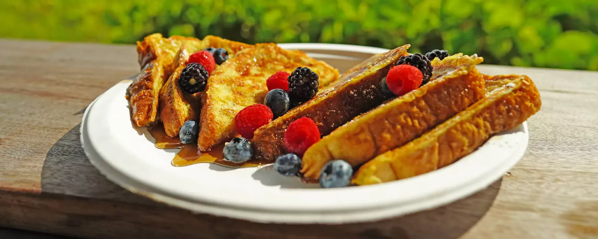 French Toast topped with syrup, raspberries, blueberries, and blackberries.
