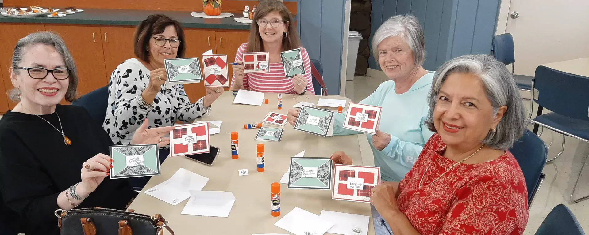 Image of a group of women holding up the holiday cards they decorated at the Log Cabin Senior Center at Langford Park in Jensen Beach, FL.