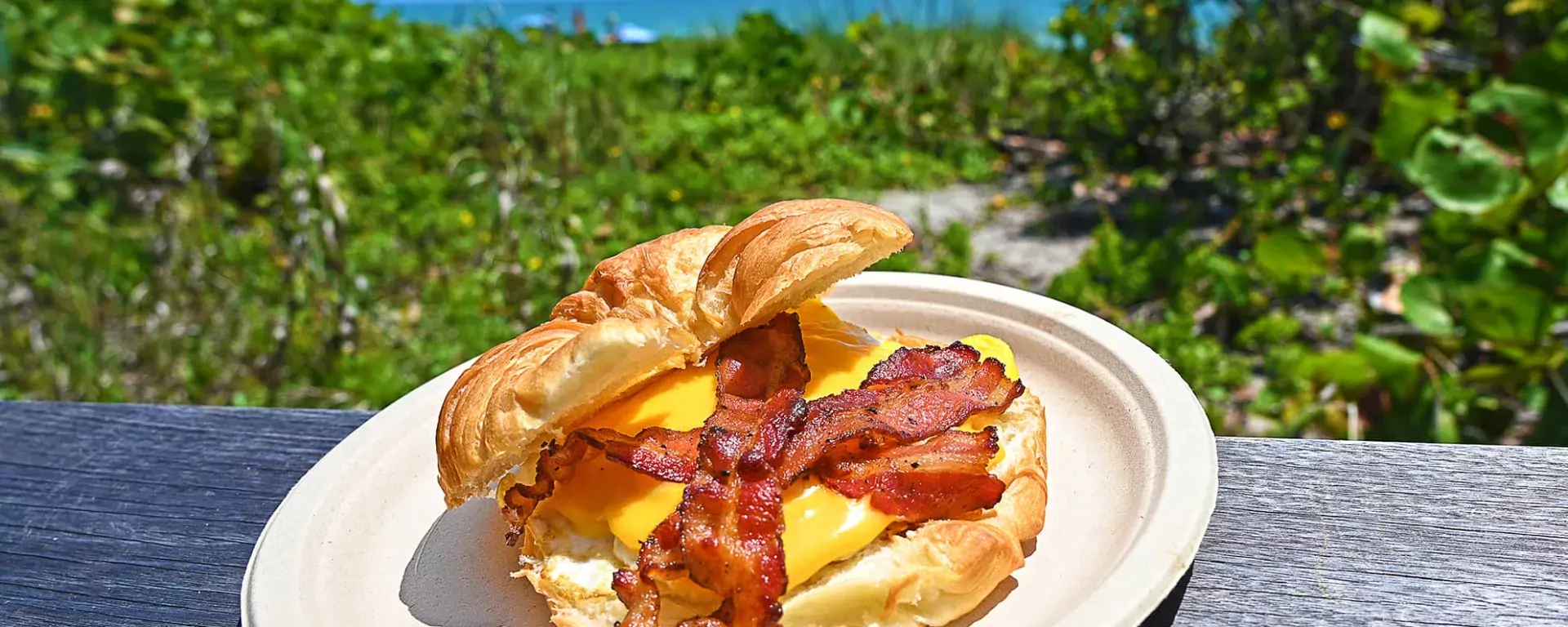 Image of a bacon, egg, and cheese breakfast sandwich on a croissant served at Sand Dune Café in Jensen Beach, FL.  