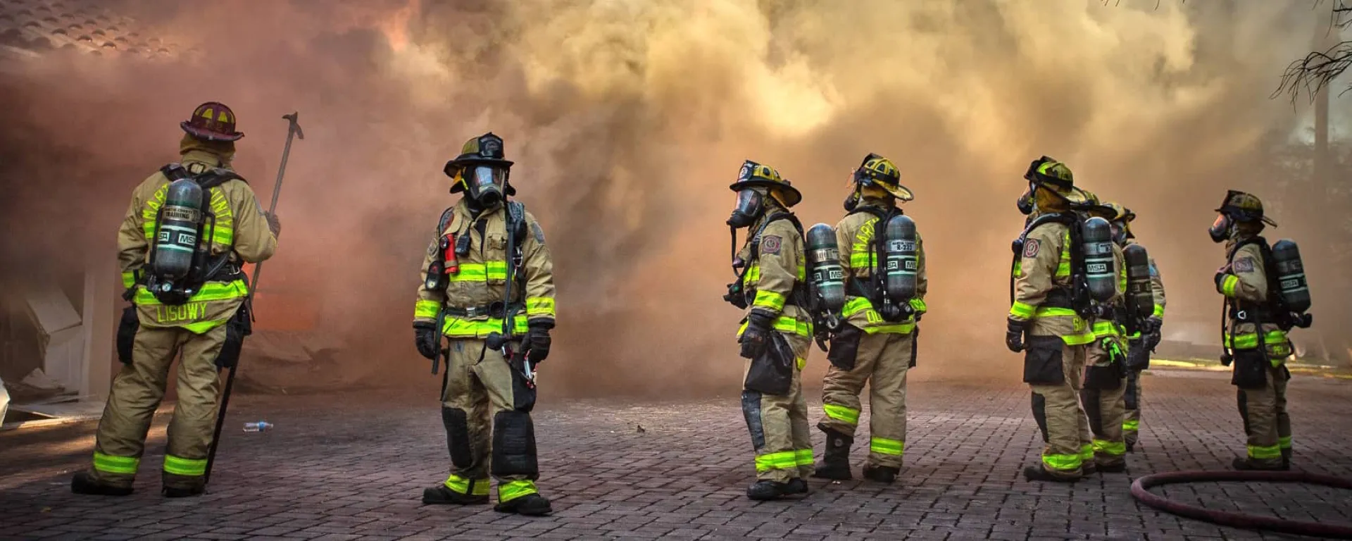 A group of firefighters with smoke behind them