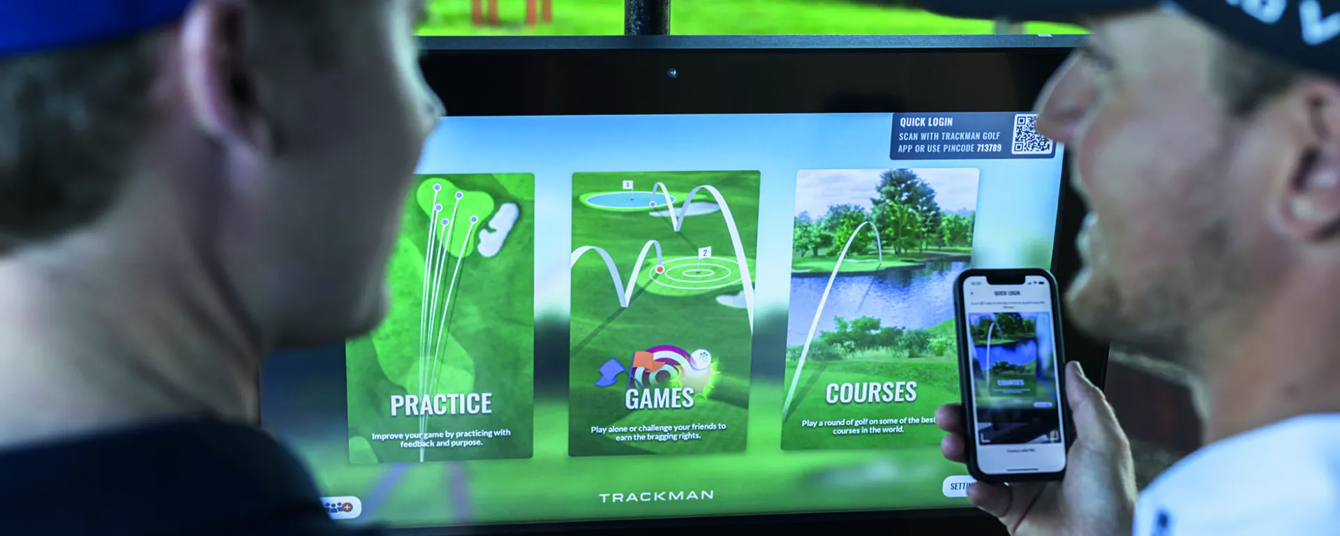 Two golfers in front of hitting bay screen