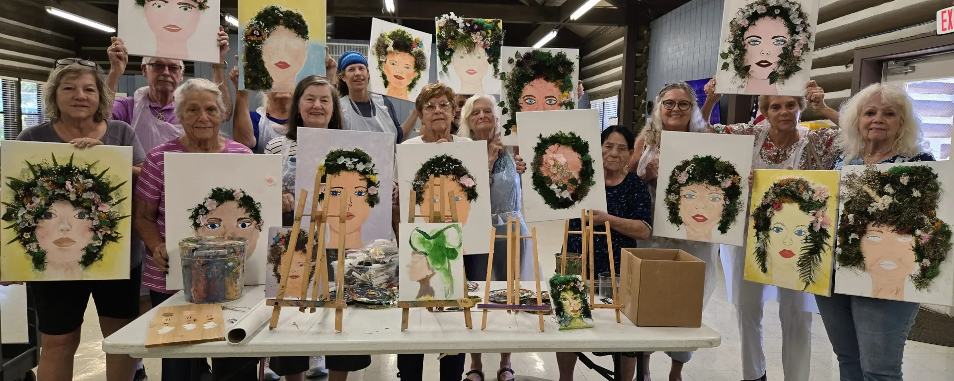 Group of seniors holding their paintings from an art class at the log cabin senior center