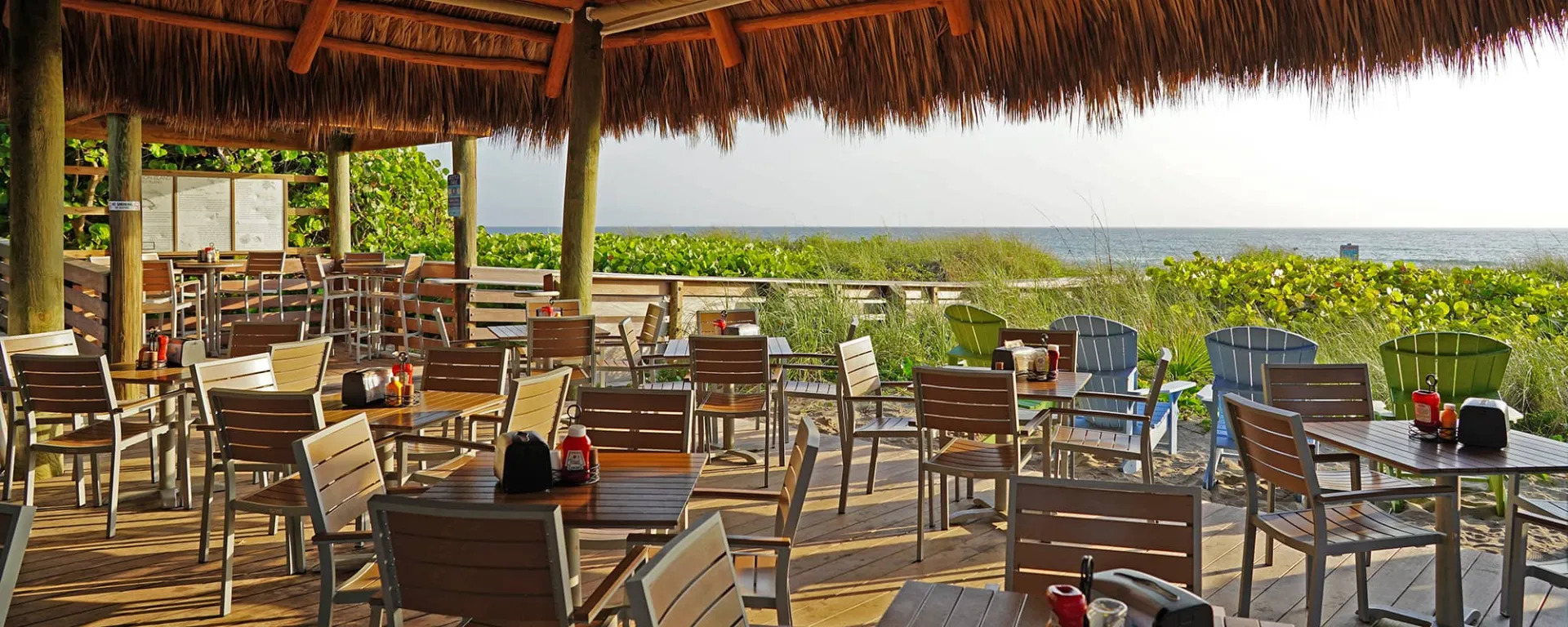 Inside Seaside Café with tables and chairs. Sand dune and ocean behind.