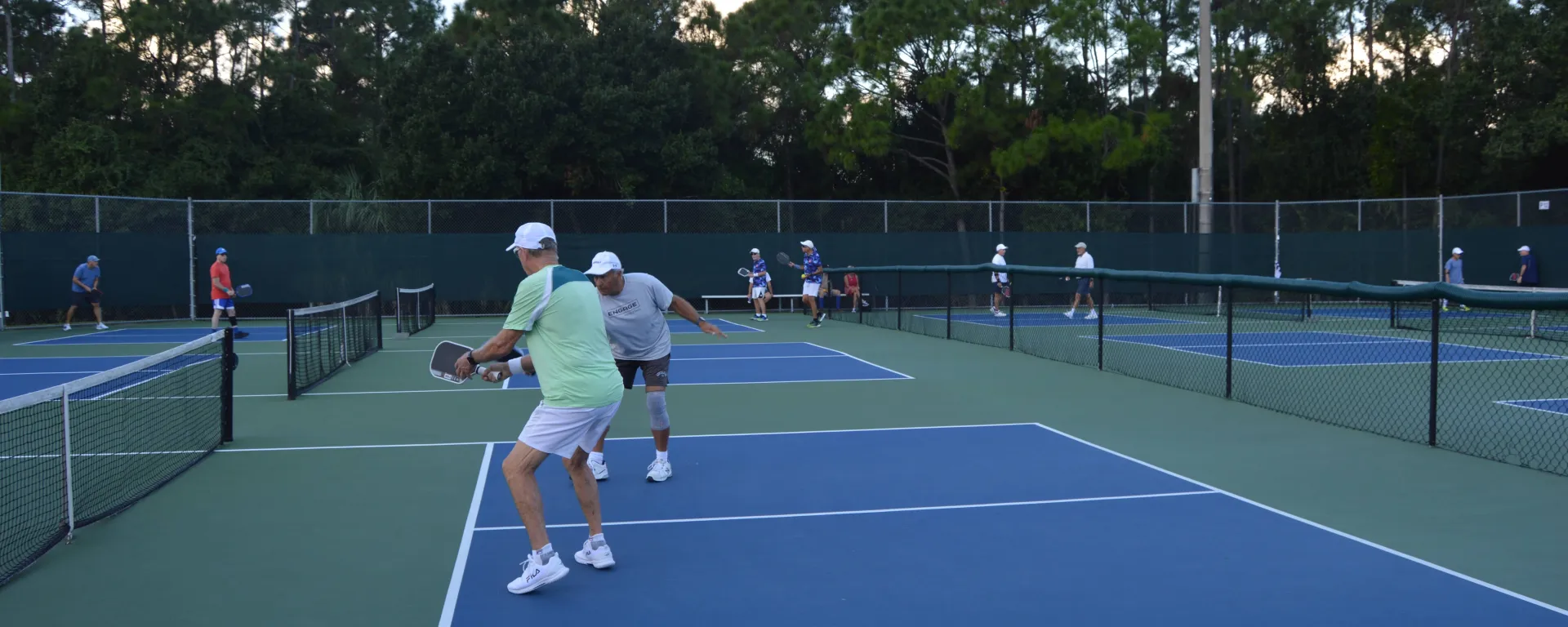 People playing in 3 pickleball courts