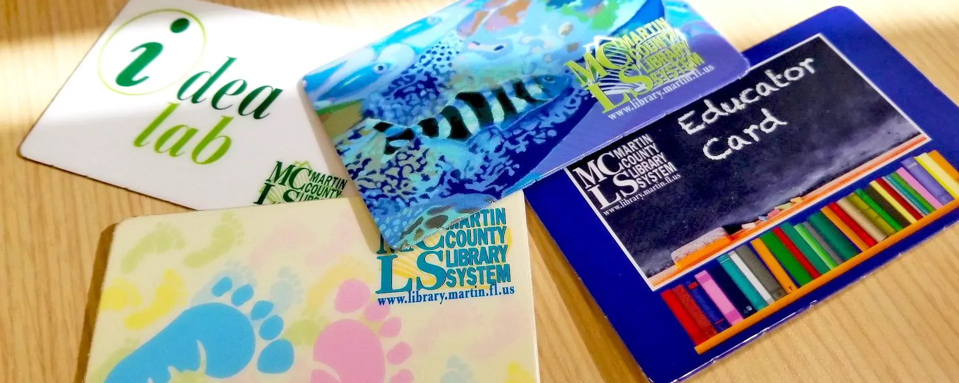 Image of four types of martin county library cards. The classic card, educator card, idea lab card, and baby card.