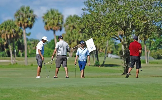 A group of golfers putting on the green.