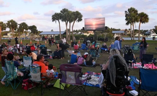A group of people gathered on blankets and chairs to watch a free community movie.