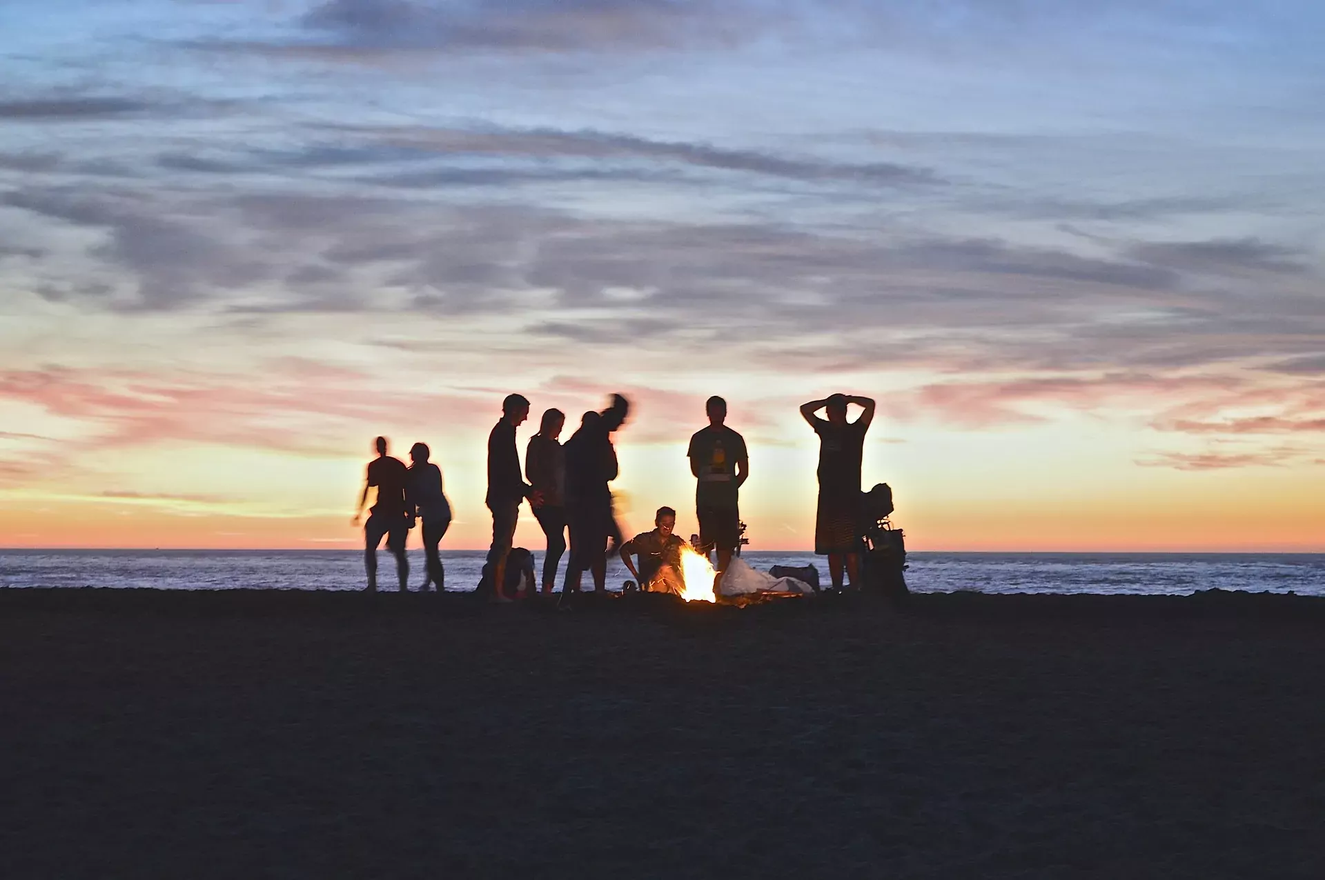 A group gathered around a beach fire