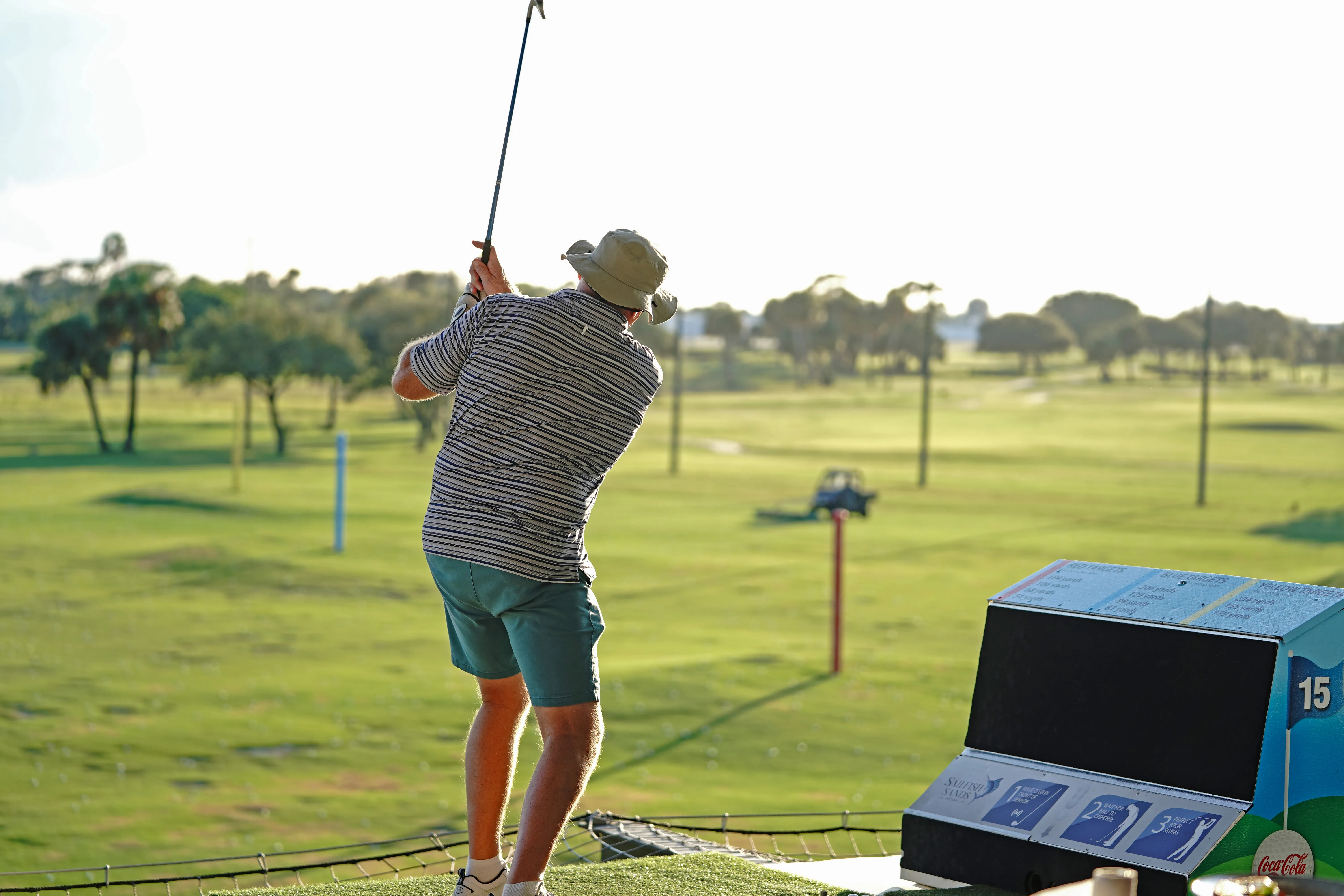 Person swinging a golf club in the hitting bays at Sailfish Sands