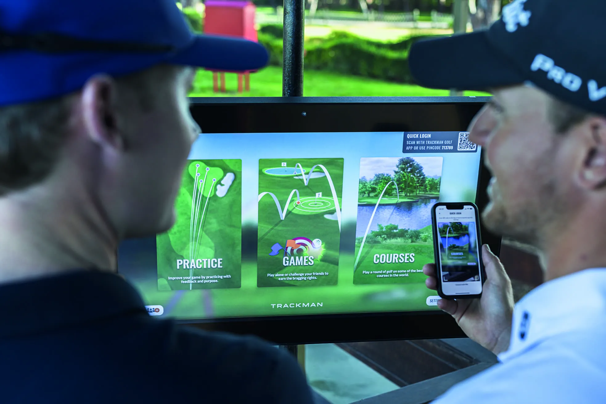 Two golfers in front of hitting bay screen