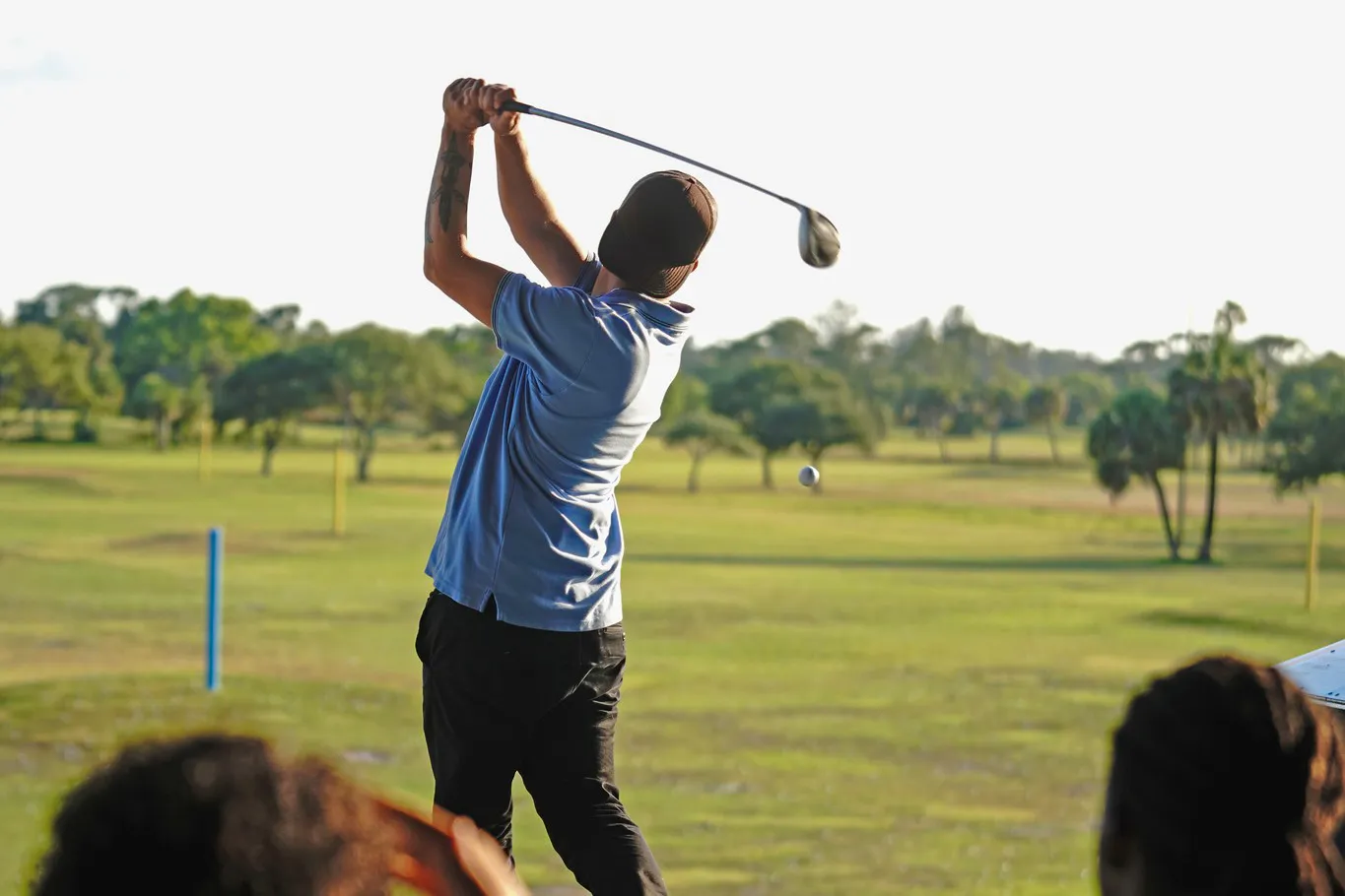 A person swinging a golf club in the hitting bays at Sailfish Sands