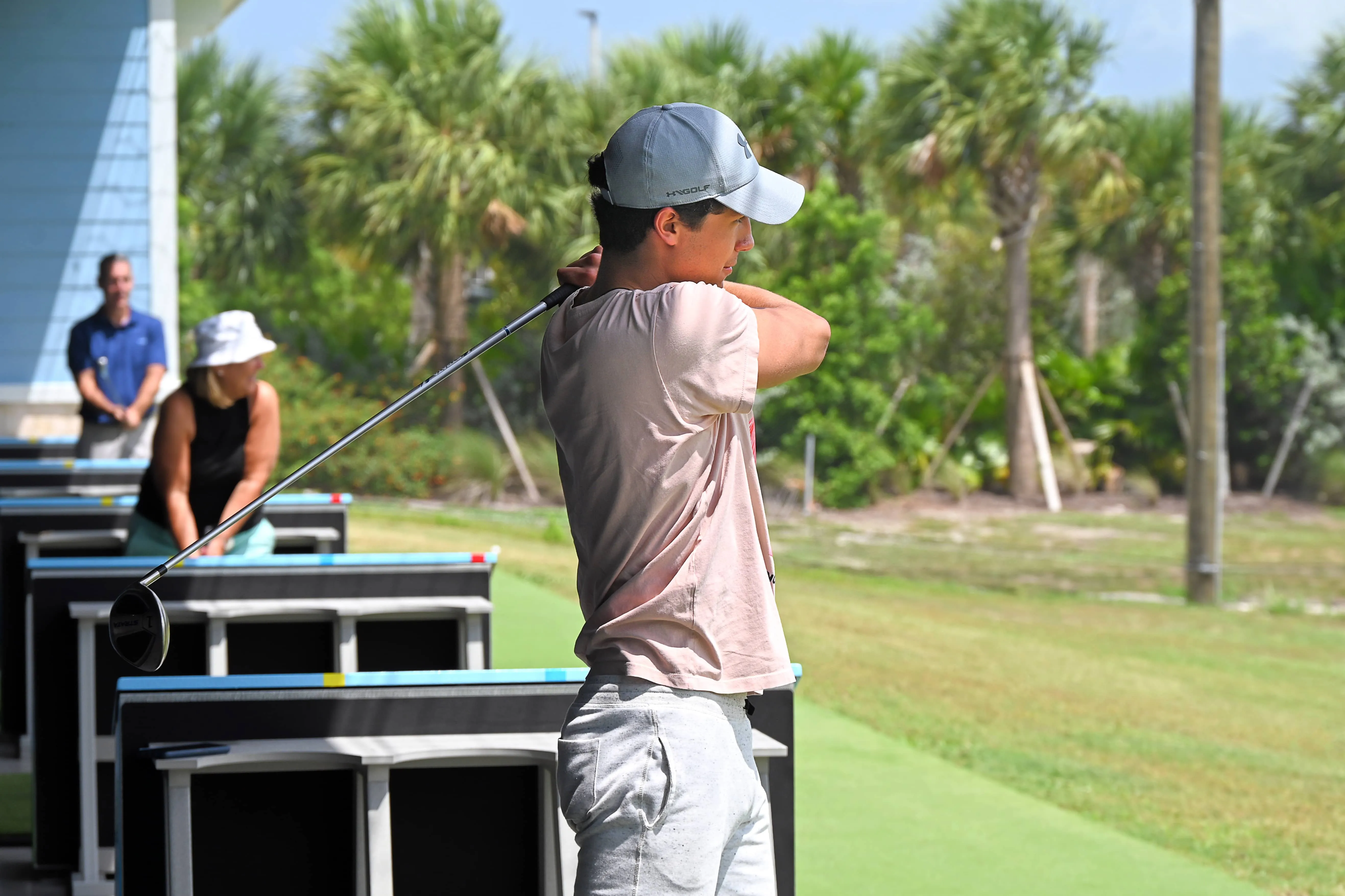 3 people swinging a golf club in the hitting bays at Sailfish Sands