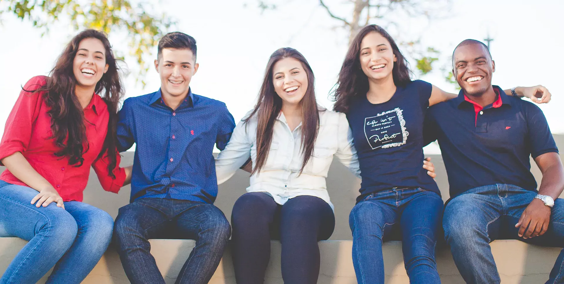 Five happy people sitting on a long couch
