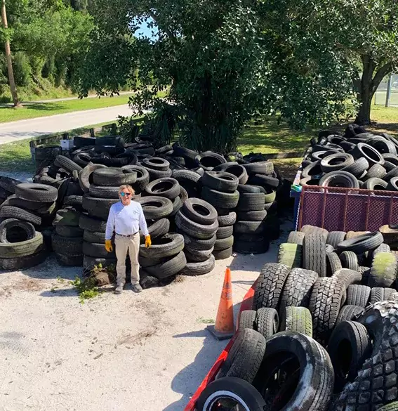 A man standing in front of hundreds of tires to be recycled