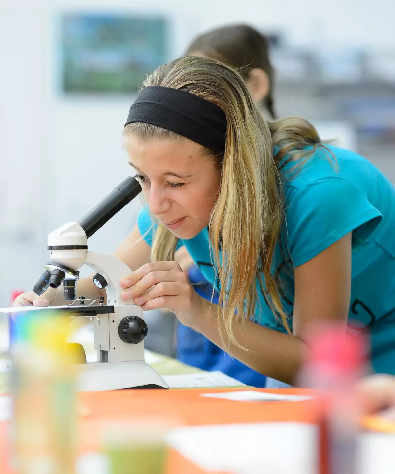 pircure of a teenage girl looking through a microscope during a library event
