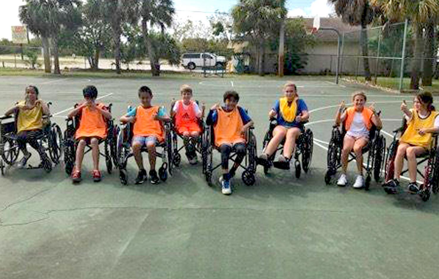 Teens posing for a photo after a wheelchair basketball game.
